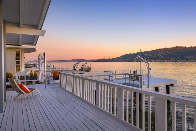 deck at dusk featuring a water view