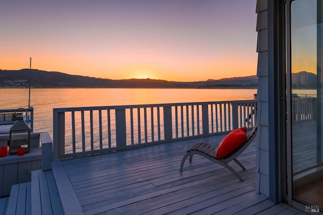 deck at dusk featuring a water view