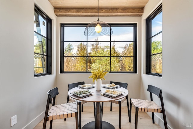 dining area featuring beam ceiling, light hardwood / wood-style flooring, and wooden ceiling