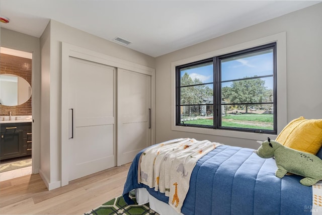 bedroom with ensuite bath, sink, a closet, and light hardwood / wood-style flooring