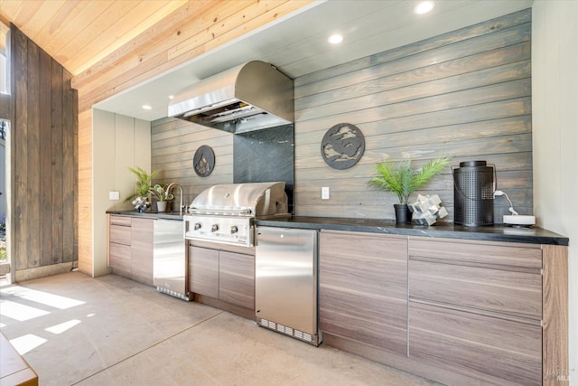 kitchen with stainless steel fridge, wooden walls, wood ceiling, and wall chimney range hood