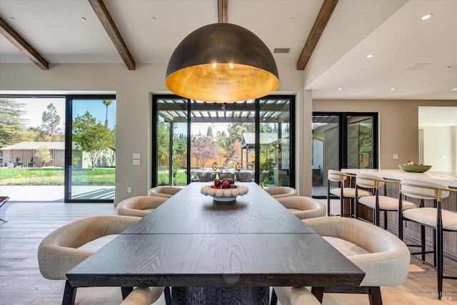 dining space featuring plenty of natural light, lofted ceiling with beams, and light hardwood / wood-style flooring