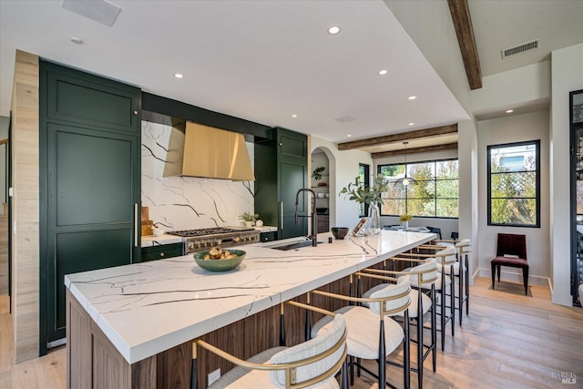 kitchen with beam ceiling, light stone countertops, sink, and green cabinetry