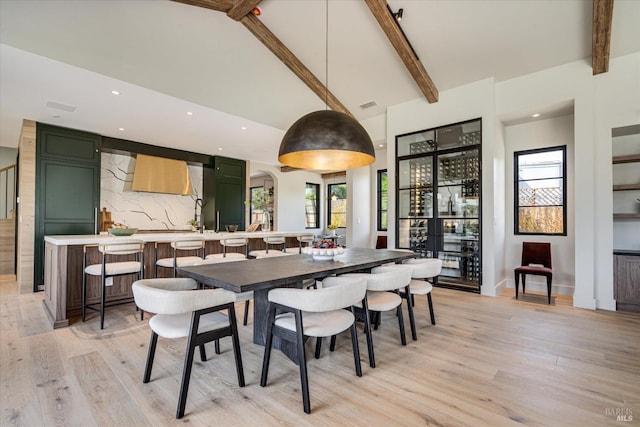 dining area featuring beamed ceiling, light hardwood / wood-style floors, and high vaulted ceiling