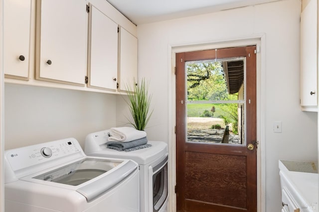 clothes washing area with washer and dryer and cabinets