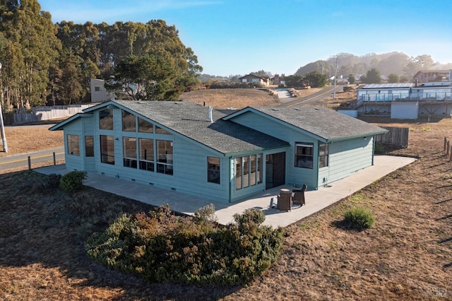 rear view of property featuring fence, a shingled roof, a patio area, and a mountain view