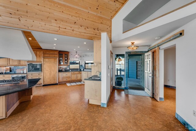 kitchen with dark countertops, a barn door, glass insert cabinets, and light floors