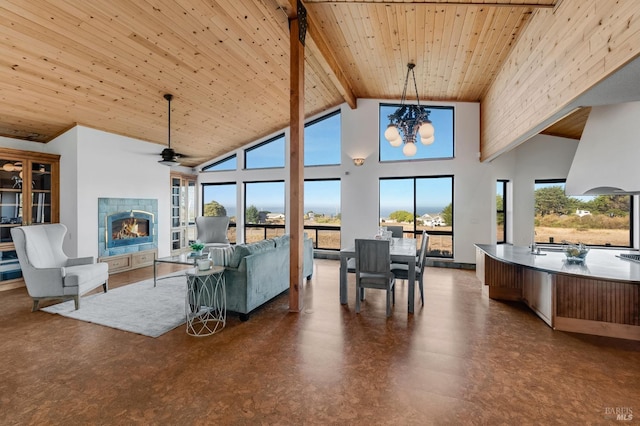 living area with wooden ceiling, ceiling fan with notable chandelier, high vaulted ceiling, a lit fireplace, and beamed ceiling