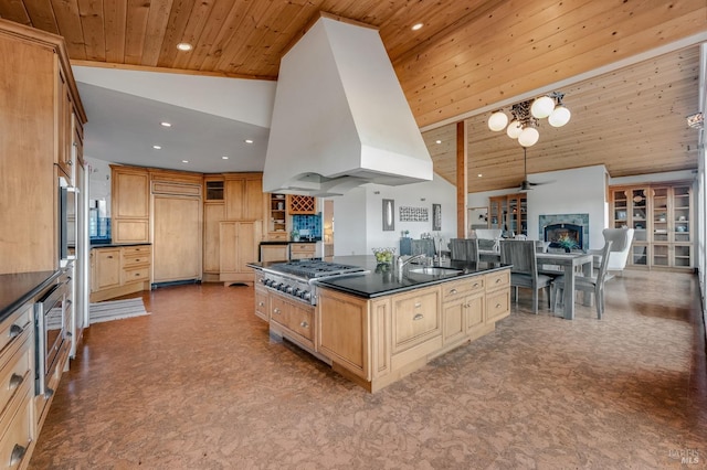 kitchen with paneled fridge, island exhaust hood, wood ceiling, stainless steel gas stovetop, and dark countertops