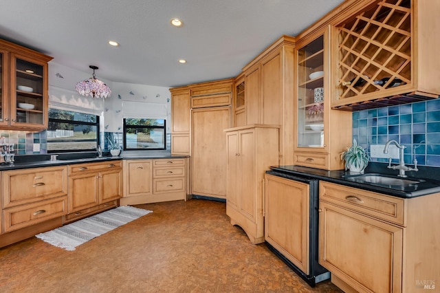 kitchen featuring glass insert cabinets, a sink, dark countertops, and tasteful backsplash
