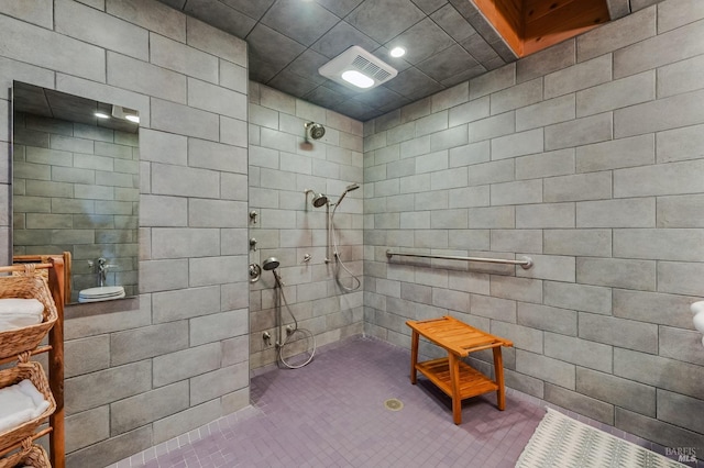 bathroom with a tile shower, tile walls, and tile patterned flooring