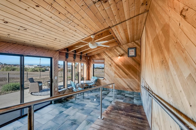 interior space featuring wood ceiling, an upstairs landing, vaulted ceiling with beams, and wooden walls
