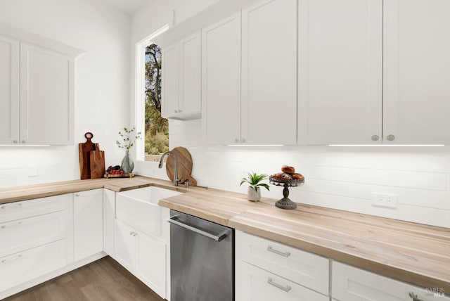 kitchen with butcher block countertops, stainless steel dishwasher, white cabinetry, and sink