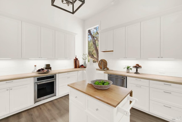 kitchen featuring butcher block counters, white cabinetry, dark wood-type flooring, tasteful backsplash, and appliances with stainless steel finishes