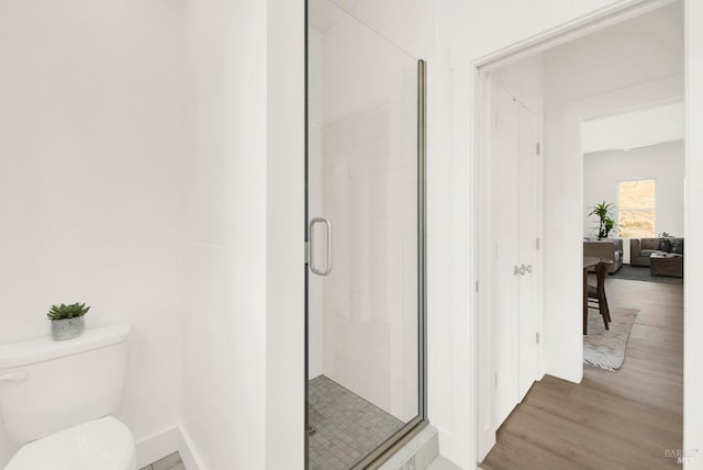 bathroom with hardwood / wood-style flooring, toilet, and a shower with shower door