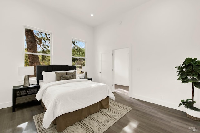 bedroom with a towering ceiling, baseboards, dark wood-style floors, and recessed lighting