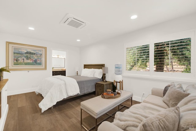 bedroom with ensuite bath and dark hardwood / wood-style floors