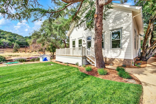 view of property exterior featuring a lawn, a storage shed, and a deck