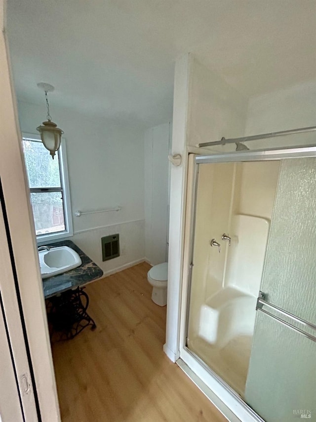 bathroom featuring an enclosed shower, sink, hardwood / wood-style floors, and toilet