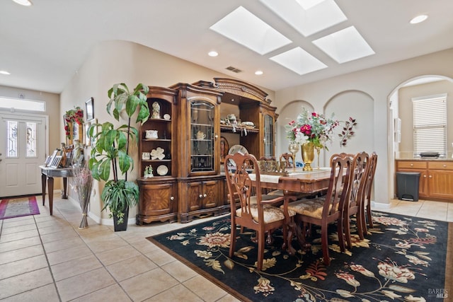 tiled dining space featuring vaulted ceiling with skylight and a healthy amount of sunlight