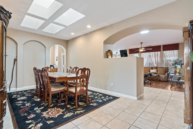 dining space featuring arched walkways, recessed lighting, light tile patterned flooring, and baseboards