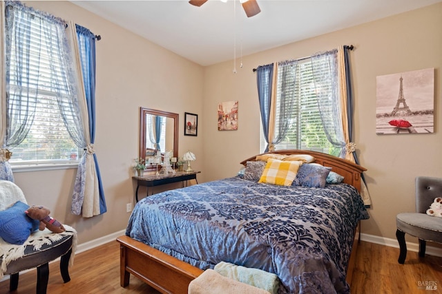 bedroom with multiple windows, wood finished floors, and baseboards