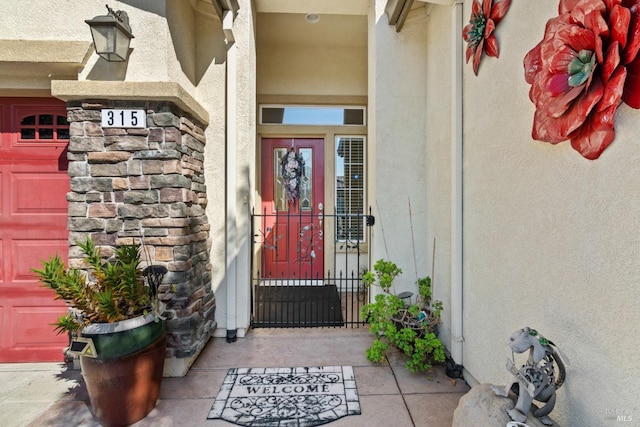 view of exterior entry with a garage and stucco siding