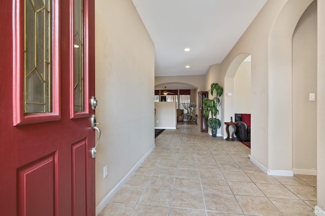 entryway featuring light tile patterned floors, baseboards, arched walkways, and recessed lighting