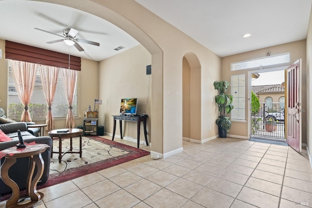 entrance foyer featuring light tile patterned floors, baseboards, visible vents, arched walkways, and a ceiling fan