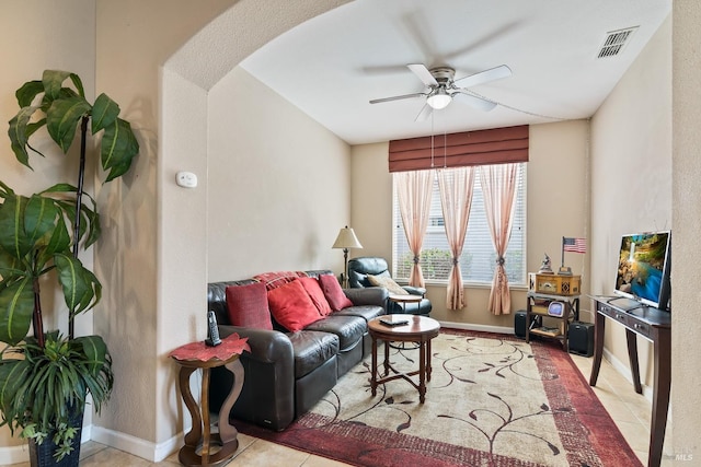 tiled living area featuring baseboards, visible vents, arched walkways, and a ceiling fan