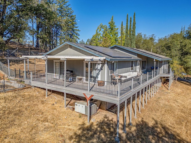 view of front of property with fence, a deck, and solar panels