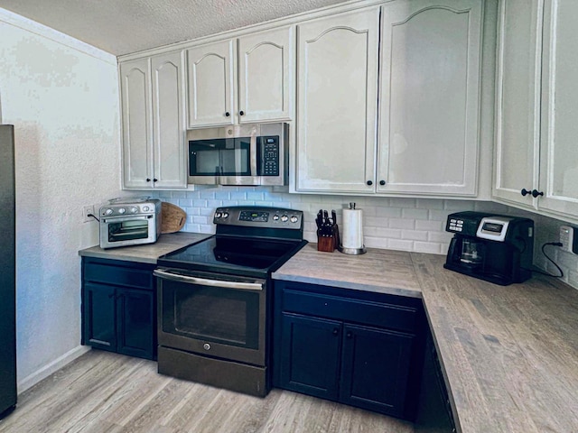 kitchen featuring appliances with stainless steel finishes, backsplash, a textured ceiling, white cabinets, and light hardwood / wood-style flooring