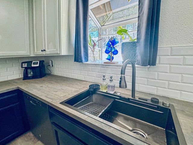 kitchen featuring black dishwasher, white cabinetry, backsplash, and a sink