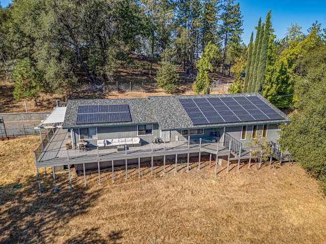 back of property with solar panels and a wooden deck