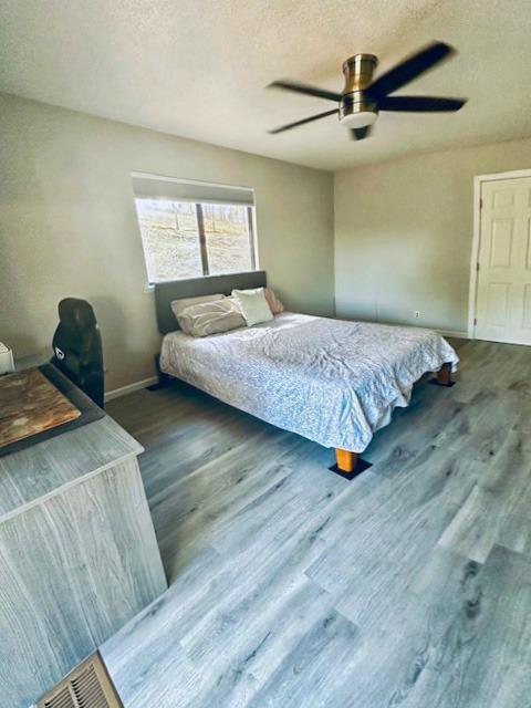 bedroom with a textured ceiling, dark hardwood / wood-style floors, and ceiling fan