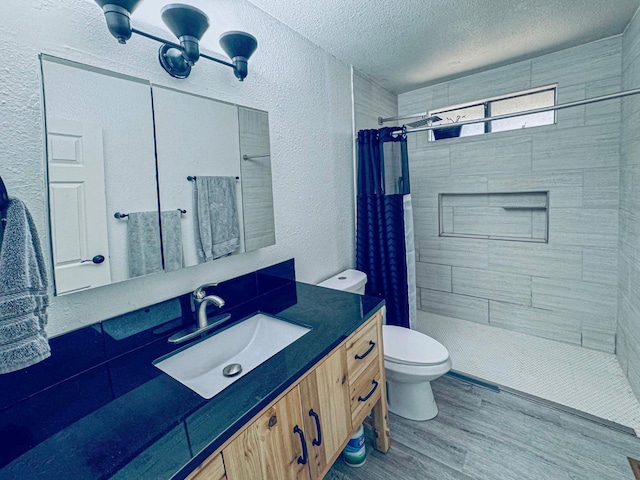 full bathroom featuring a textured wall, toilet, a tile shower, a textured ceiling, and wood finished floors