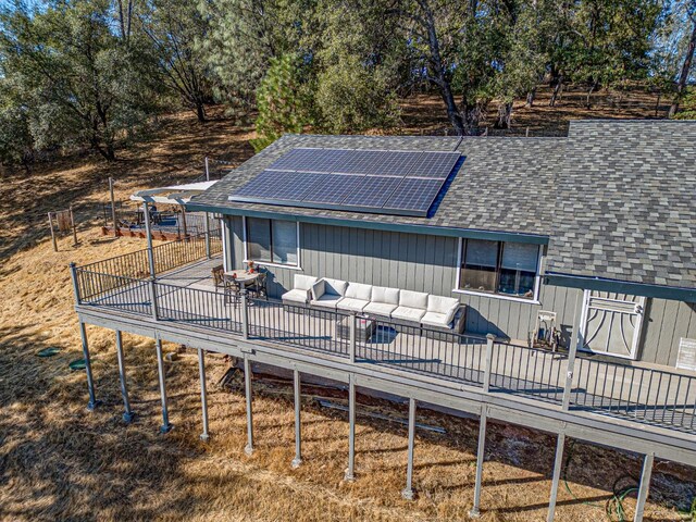 back of property with a wooden deck, solar panels, and outdoor lounge area