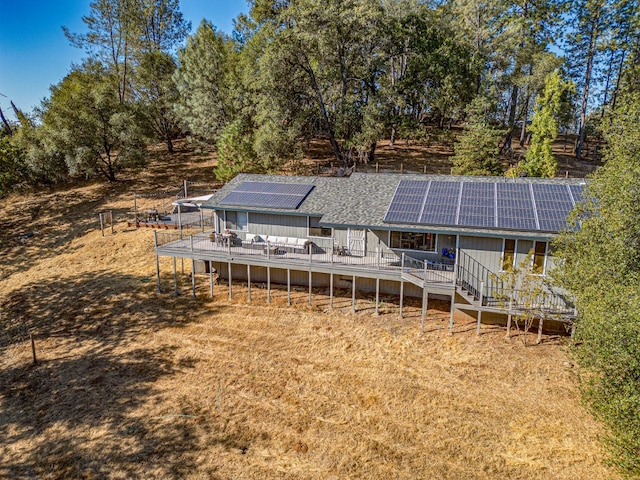 rear view of house with roof with shingles, stairway, a wooden deck, and solar panels