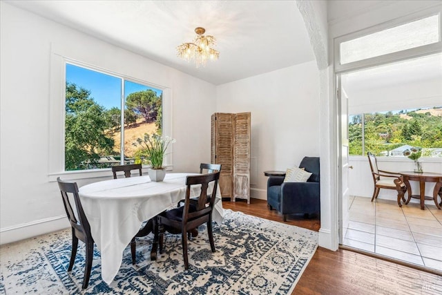 dining area with wood finished floors, baseboards, and an inviting chandelier