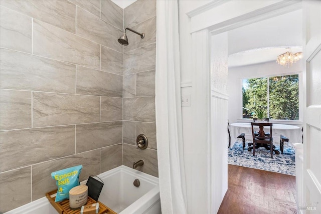 full bathroom featuring wood finished floors, bathtub / shower combination, and an inviting chandelier