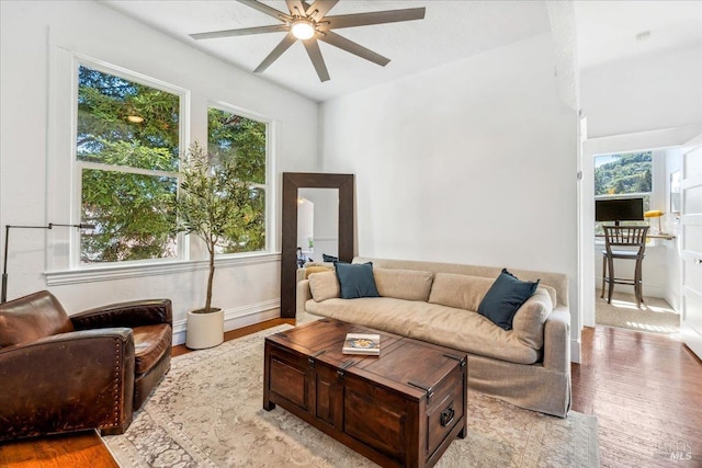 living area with a ceiling fan, light wood-style flooring, and baseboards