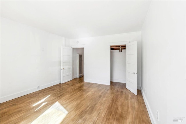 unfurnished bedroom featuring light wood-style floors, baseboards, and a closet