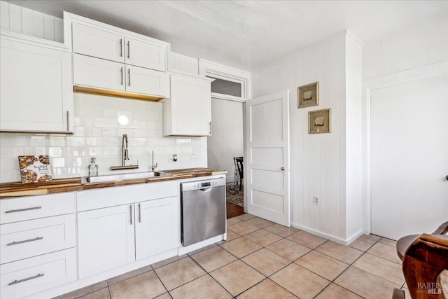 kitchen featuring light tile patterned floors, tasteful backsplash, white cabinets, stainless steel dishwasher, and a sink