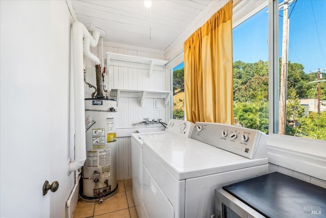 clothes washing area featuring light tile patterned floors, laundry area, washer and clothes dryer, and gas water heater