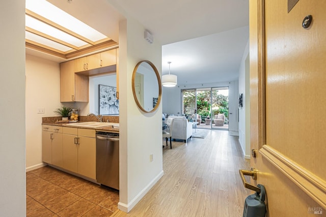 kitchen featuring hanging light fixtures, cream cabinetry, light hardwood / wood-style floors, dishwasher, and sink