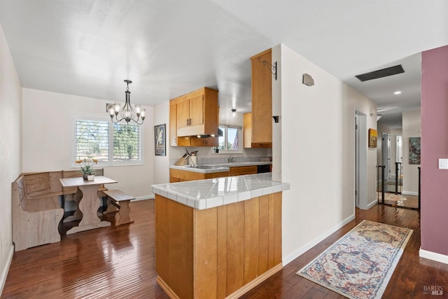 kitchen with tile countertops, kitchen peninsula, a healthy amount of sunlight, and dark hardwood / wood-style floors