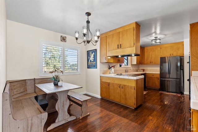 kitchen with kitchen peninsula, stainless steel fridge, an inviting chandelier, dark hardwood / wood-style floors, and hanging light fixtures