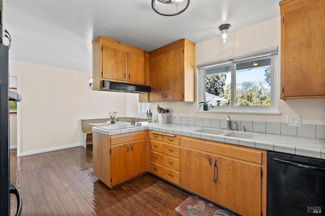 kitchen with tile counters, dishwasher, dark wood-type flooring, and sink