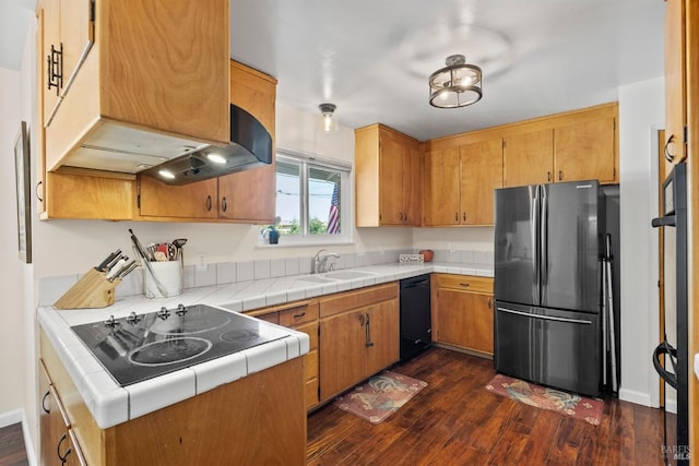 kitchen with sink, tile countertops, dishwasher, dark hardwood / wood-style floors, and stainless steel refrigerator