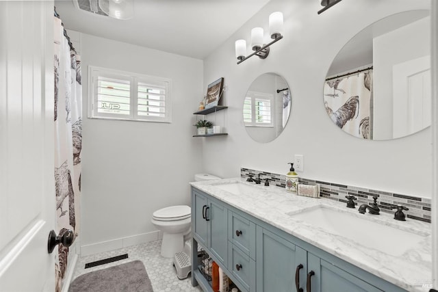 bathroom with decorative backsplash, vanity, a healthy amount of sunlight, and toilet